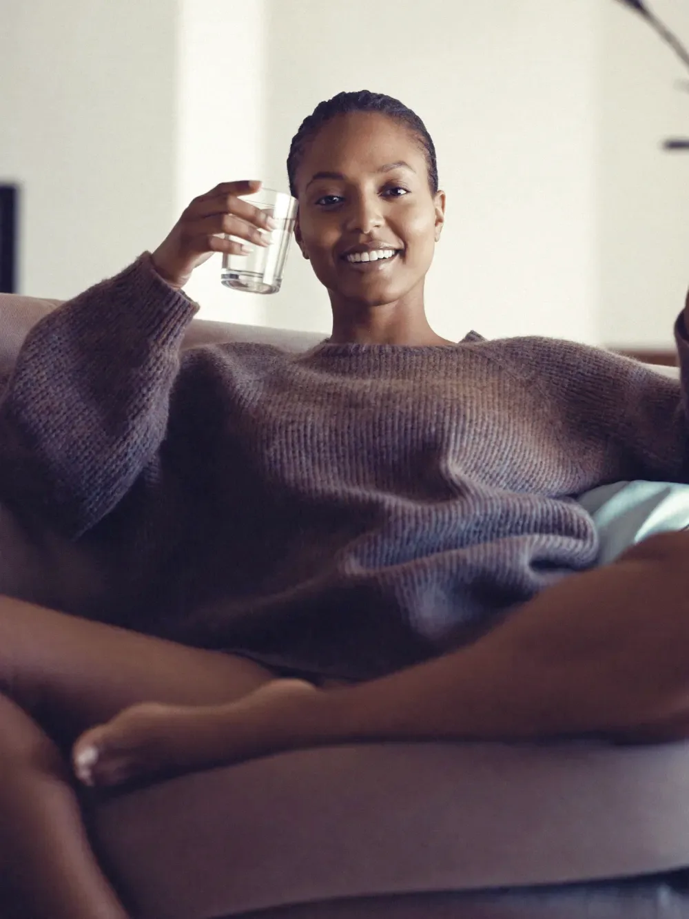A confident, healthy person relaxed at home with a glass of water