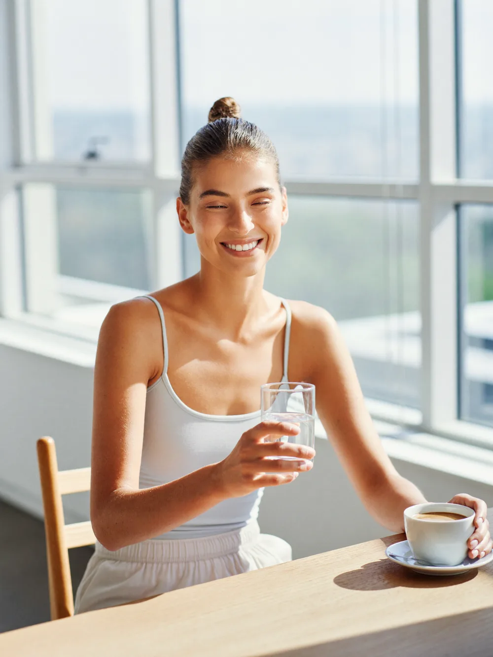 A calm person holding a warm mug by a window in morning light